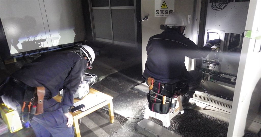 夜間にキュービクルで試験作業を行う電気工事士2名