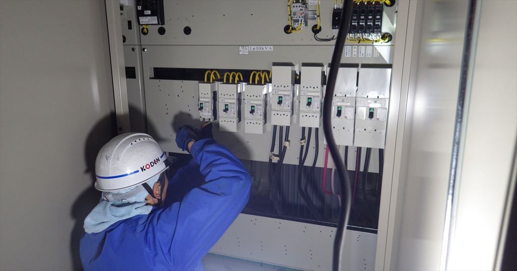 新しいキュービクルの低圧側で結線作業を行う電気工事士
