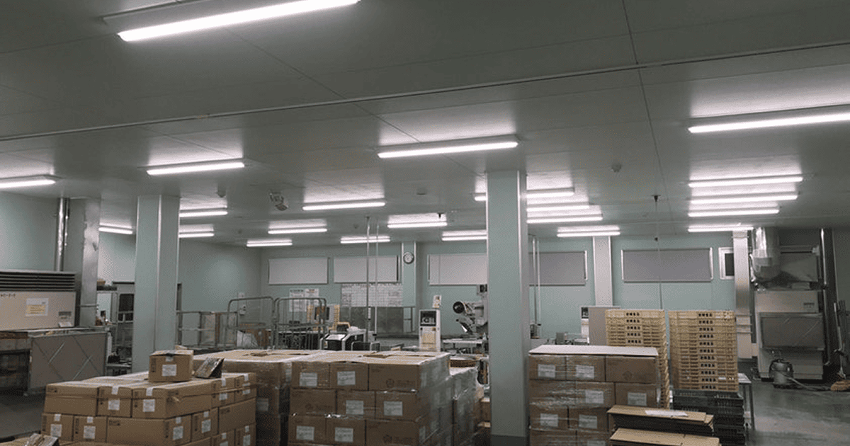 LED照明に交換した工場内の天井照明と保管された段ボール製品が並ぶ倉庫スペース