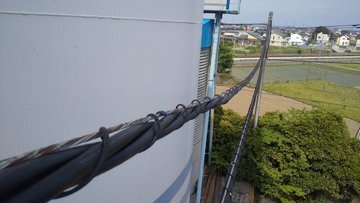 建物の上を通る架空配線の高圧ケーブル（吊り線にハンガーで吊ったもの）