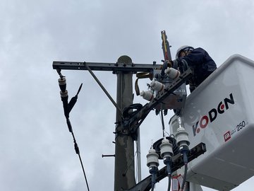 高所作業車で電柱上のPAS取付作業を行う作業員