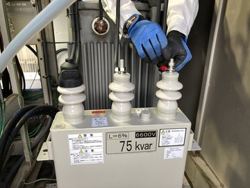 新しい高圧進相コンデンサに結線作業を行う作業員の手元