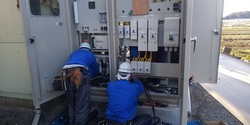 屋外に設置されたキュービクル内部で作業する2名の作業員