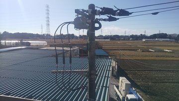 工場屋根上に設置された高圧引き込み設備と周辺の田園風景