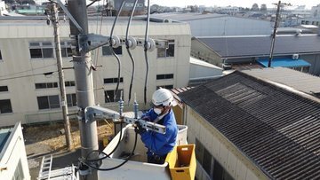 電柱上のバケットで高圧ケーブル接続作業を行う作業員