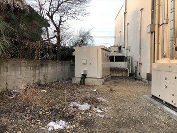 建物脇の空き地に設置されたキュービクルの外観