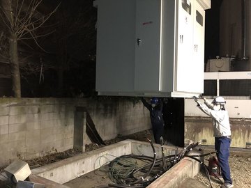 夜間にキュービクルを設置し配線接続を行う作業員たち