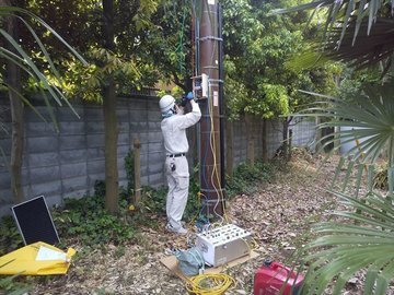電柱の下部でDGR（地絡方向継電器）の取り付け作業を行う作業員