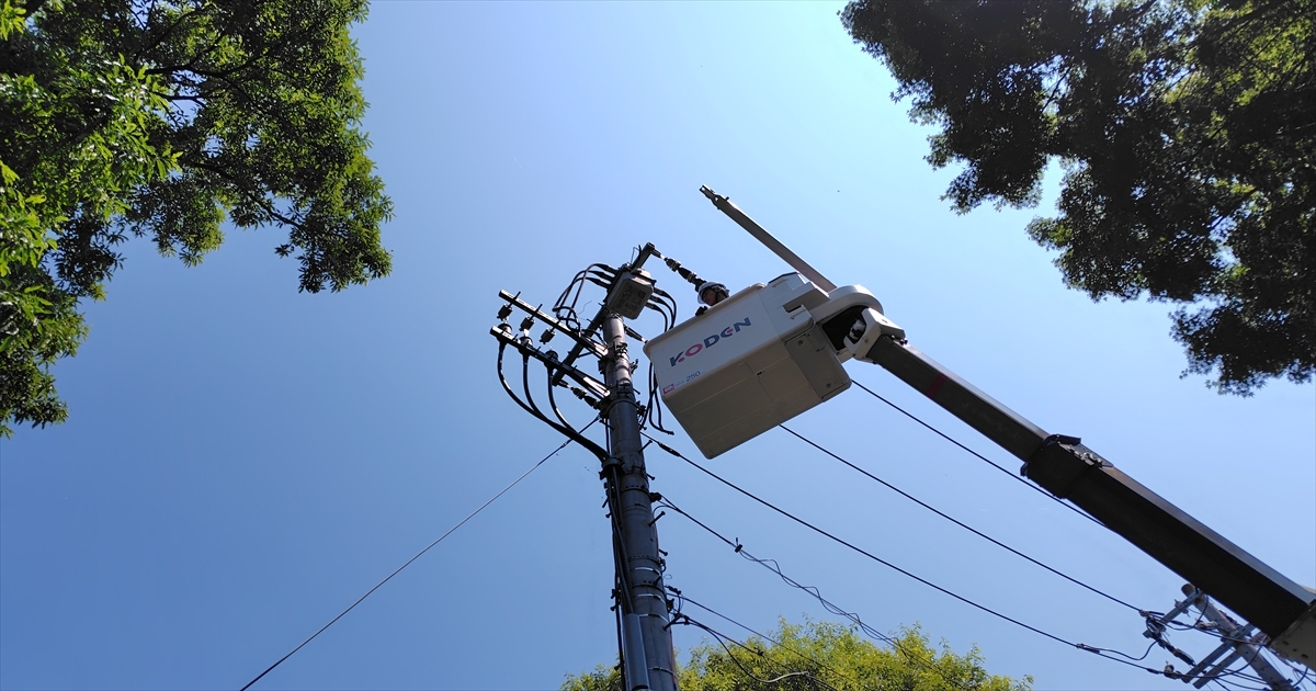 電柱脇の高所作業車バケットで作業する電気工事士