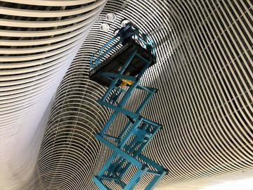 曲面の天井下でシザーリフトが作業する様子
