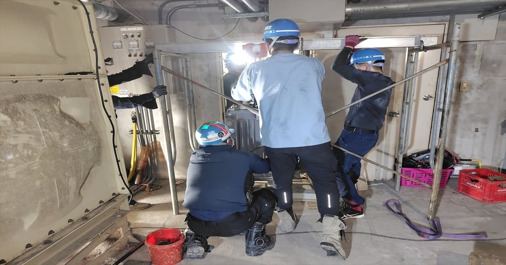 地下のキュービクル室でトランスの搬出作業をする作業員たち