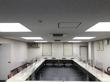 会議室の天井照明が点灯し椅子が並ぶ室内の様子