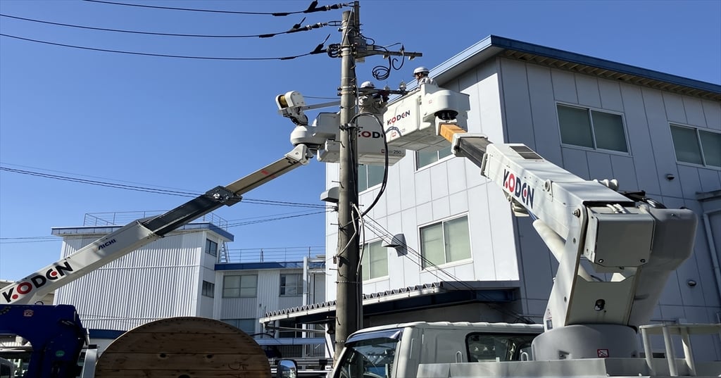 電柱の両側に高所作業車を配置して工事を行う様子
