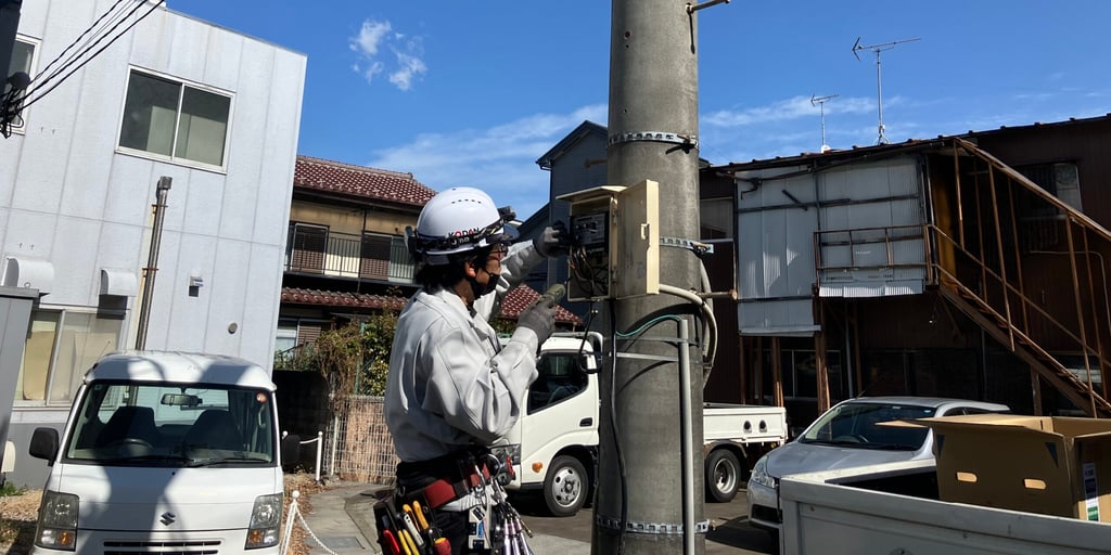 電柱の制御盤を点検する恒電社のヘルメット姿の作業員