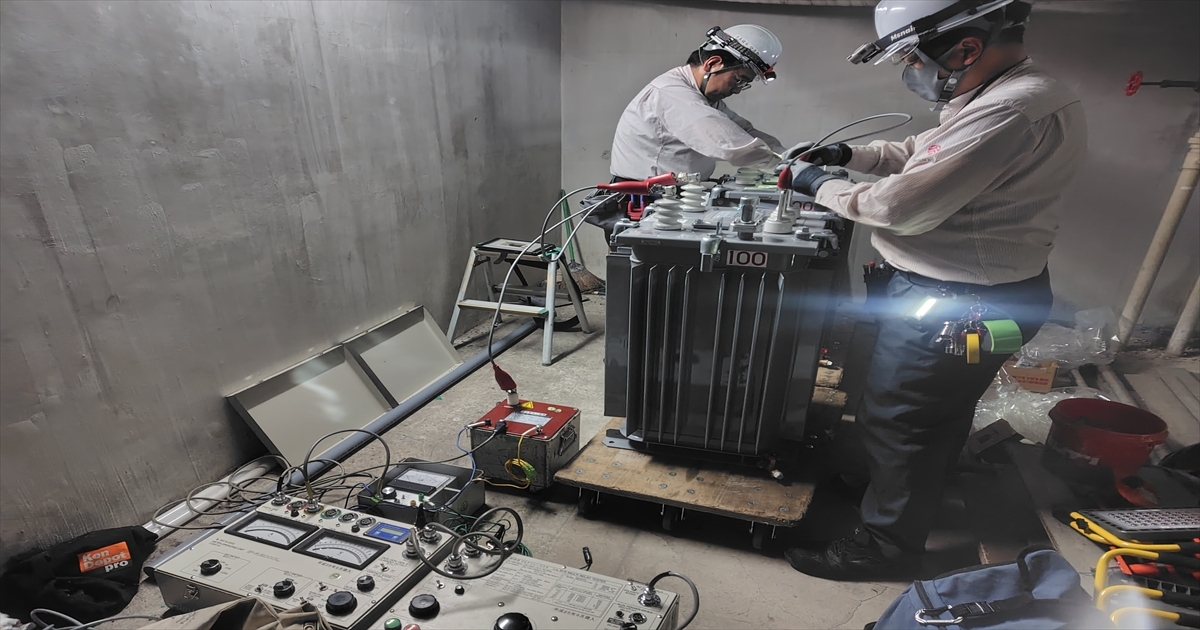 地下室でトランスの絶縁耐圧試験を行う恒電社の作業員2名