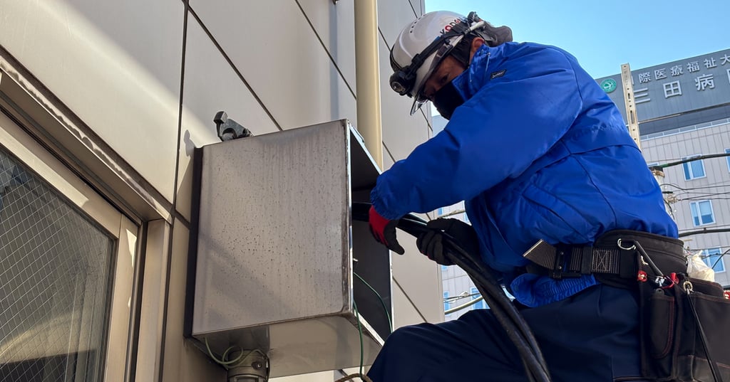 建物外壁で高圧ケーブルの引き込み作業を行う恒電社の電気工事士