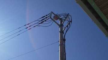 電柱上部の開閉器と碍子、配線を見上げた様子