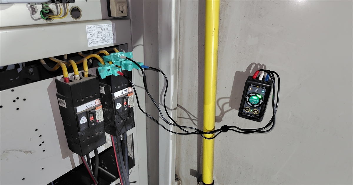 分電盤のブレーカーにクランプメーターを取り付け測定する様子