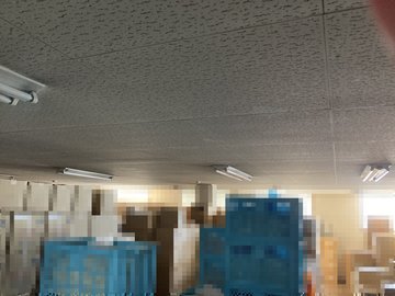 交換前：コンテナと段ボールが並ぶ保管スペースの天井照明