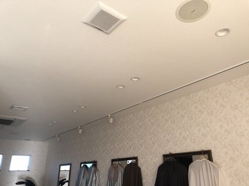 交換前の、壁際にハンガーラックが並ぶ部屋の天井照明