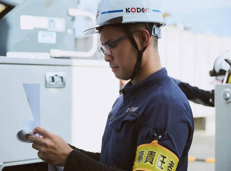 KODENのロゴが入ったヘルメットを着用して現場を確認する担当者